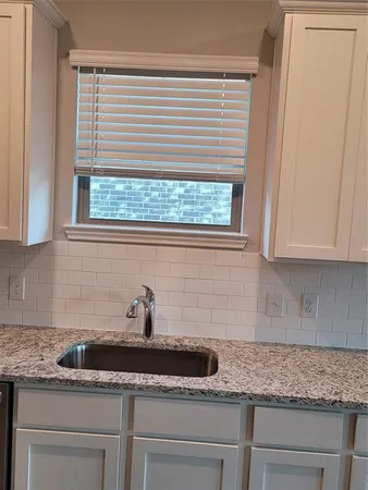 a kitchen with granite countertop white cabinets and a window