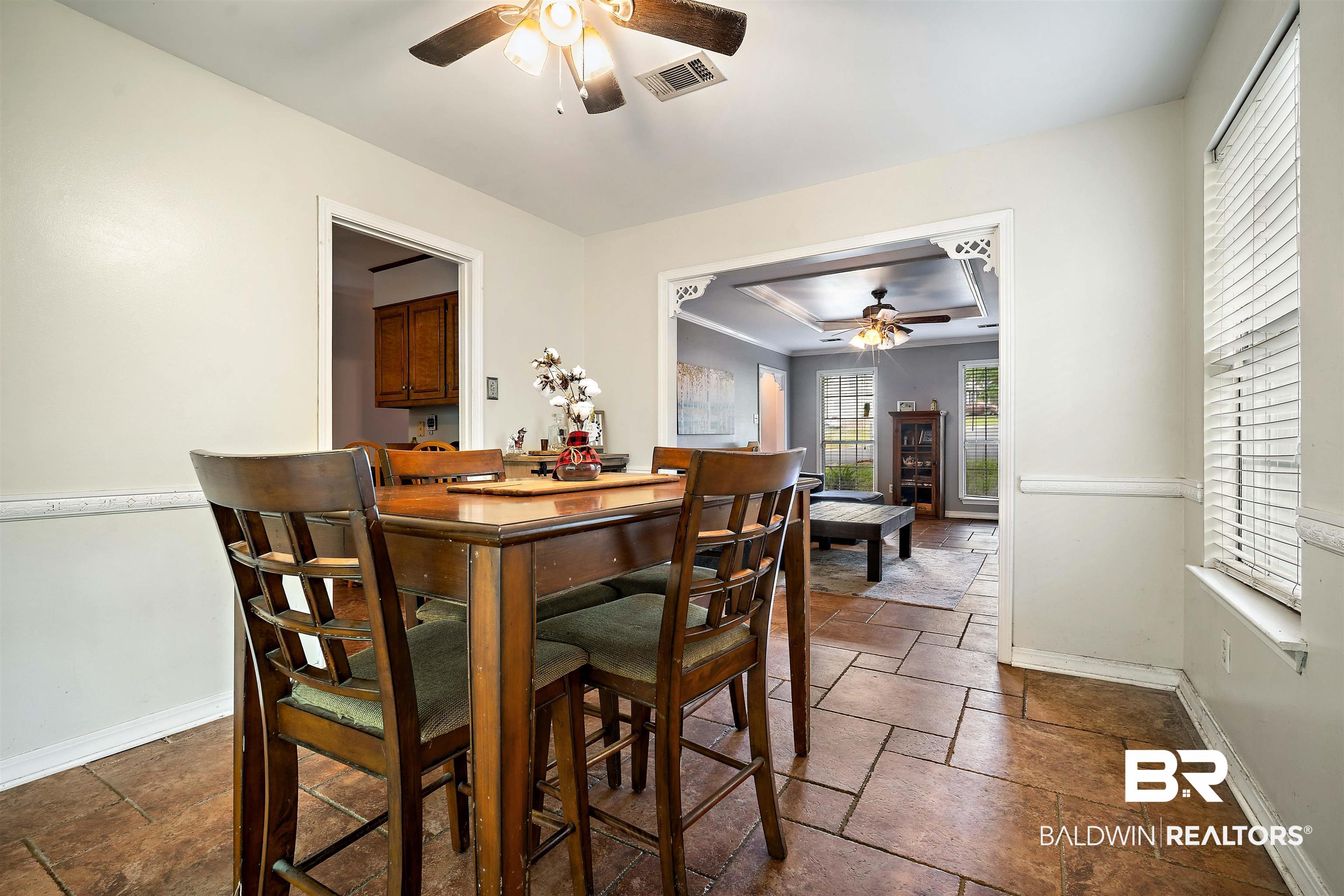 2823 Woodland Road Mobile, AL 36693 - Photo 9 of 29 Dining room featuring stone tile floors, a raised ceiling, visible vents, a ceiling fan, and baseboards