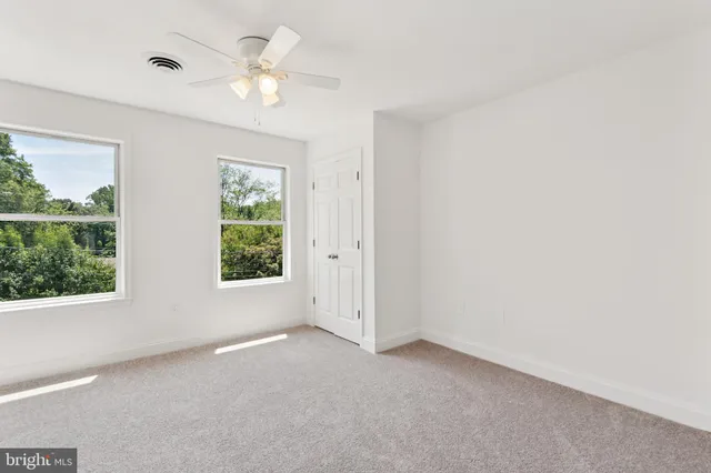 an empty room with windows and ceiling fan