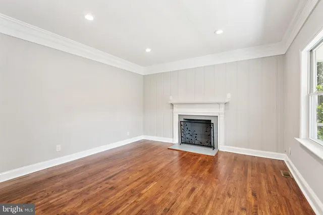 an empty room with wooden floor and fireplace