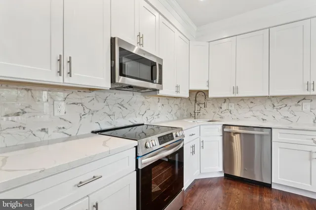 a kitchen with white cabinets stainless steel appliances and wooden floor