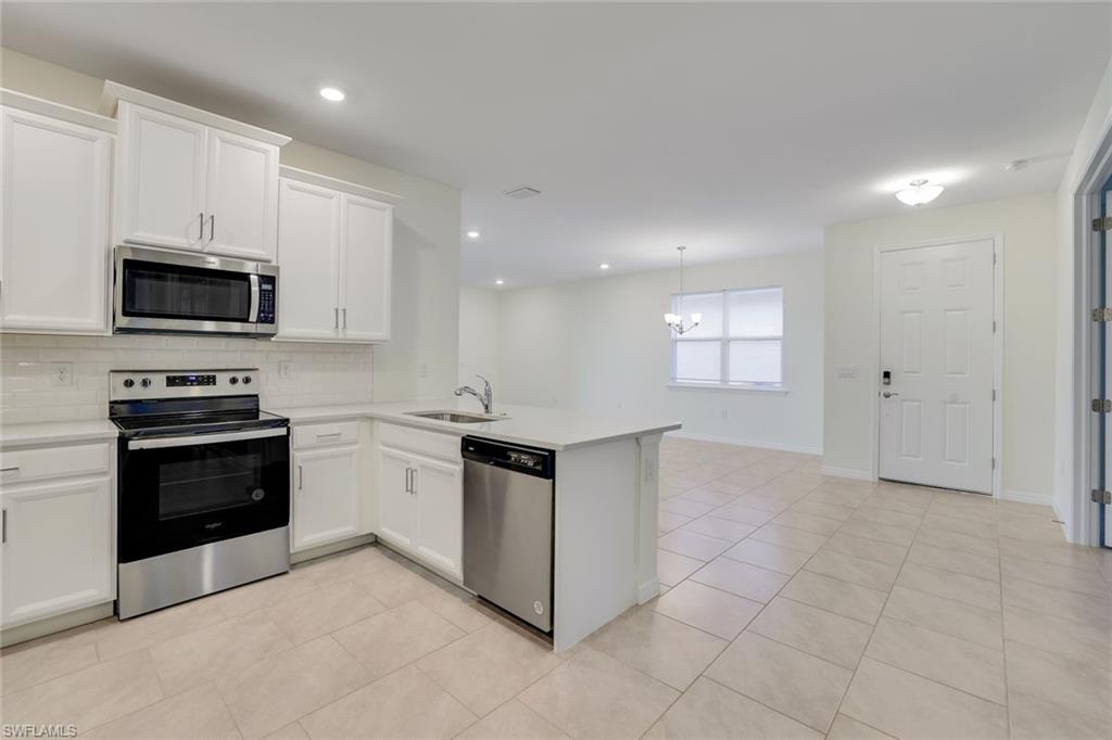 1249 Enbrook Loop Naples, FL 34114 - Photo 8 of 27 Kitchen featuring sink, kitchen peninsula, appliances with stainless steel finishes, white cabinets, and decorative backsplash