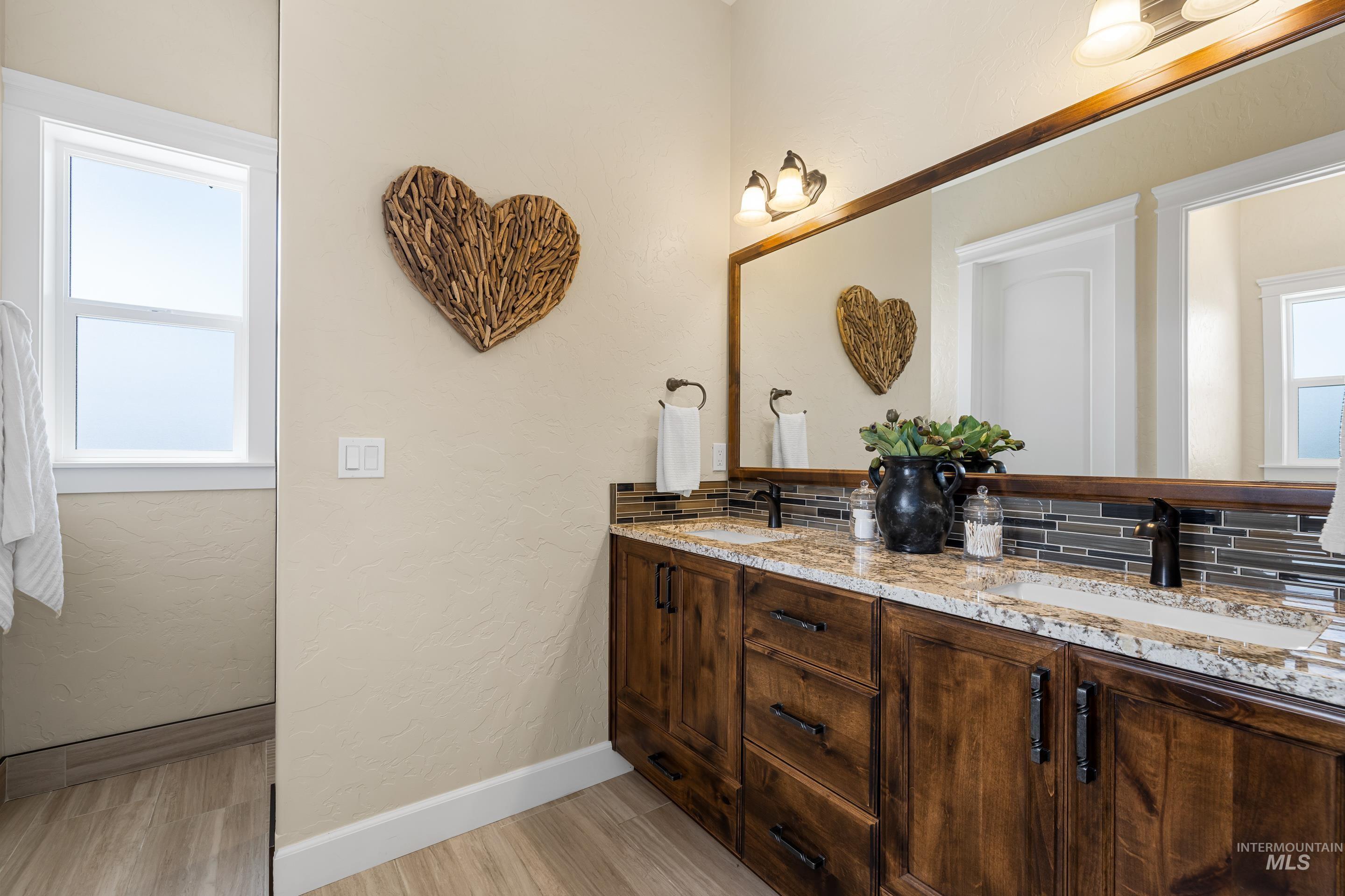 9819 Foothill Road Middleton, ID 83644 - Photo 33 of 49 Bathroom featuring double vanity, wood finished floors, a textured wall, and backsplash