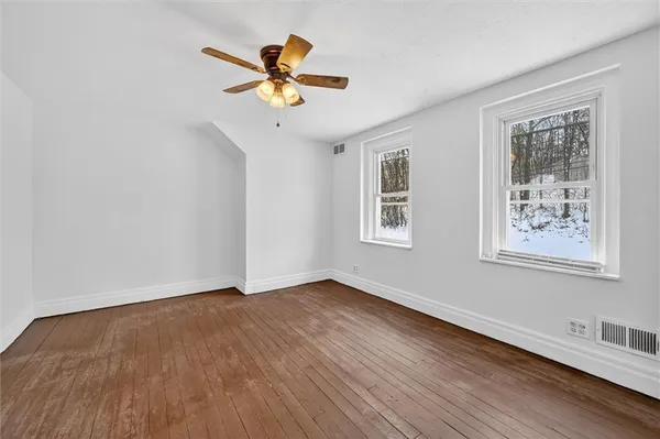 a view of room with wooden floor and ceiling fan