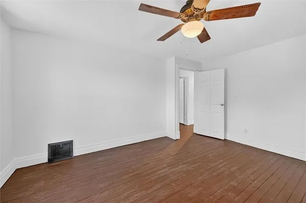 an empty room with wooden floor ceiling fan and window