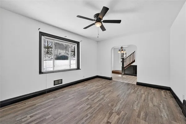 a view of empty room with wooden floor and ceiling fan