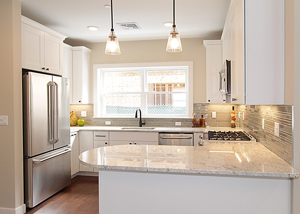 a kitchen with granite countertop a refrigerator a sink a stove and white cabinets
