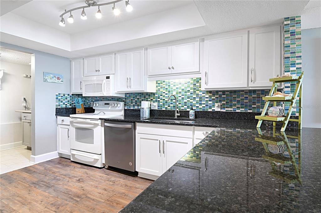 15316 Gulf Boulevard, Unit 402 Madeira Beach, FL 33708 - Photo 11 of 41 a kitchen with a white stove top oven and white cabinets