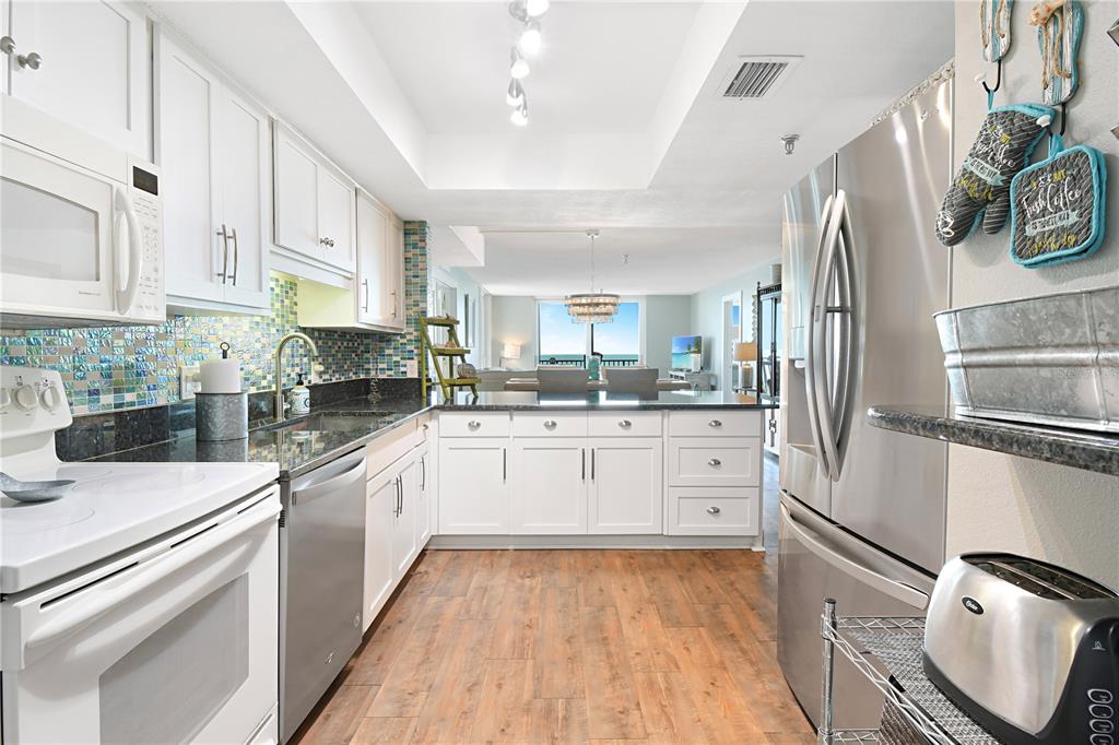15316 Gulf Boulevard, Unit 402 Madeira Beach, FL 33708 - Photo 13 of 41 a kitchen with stainless steel appliances granite countertop a refrigerator sink and white cabinets