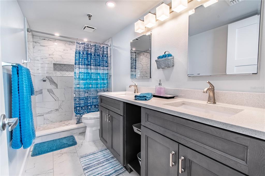 15316 Gulf Boulevard, Unit 402 Madeira Beach, FL 33708 - Photo 19 of 41 a bathroom with a sink a toilet a mirror and shower