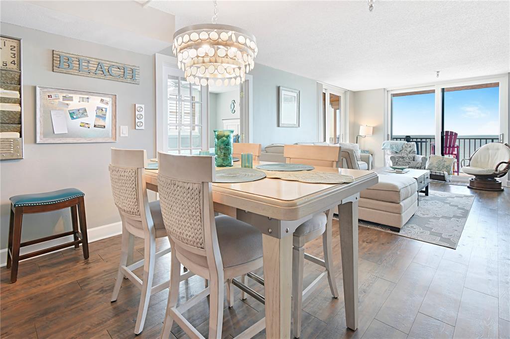 15316 Gulf Boulevard, Unit 402 Madeira Beach, FL 33708 - Photo 10 of 41 a view of a dining room with furniture a chandelier and wooden floor
