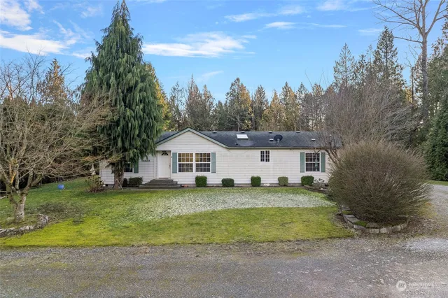 a view of a house with a big yard and large trees