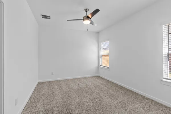 an empty room with a window and a fan