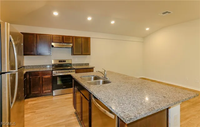a kitchen with stainless steel appliances granite countertop a sink stove and refrigerator