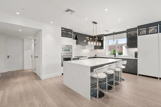 a kitchen with kitchen island wooden cabinets and refrigerator