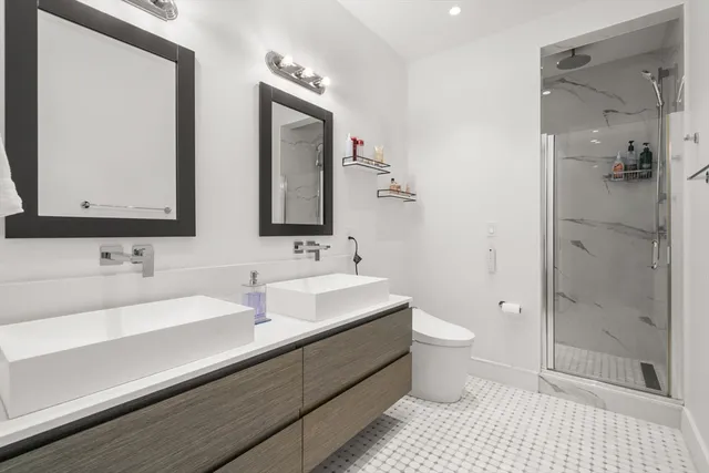 a bathroom with a double vanity sink toilet and shower