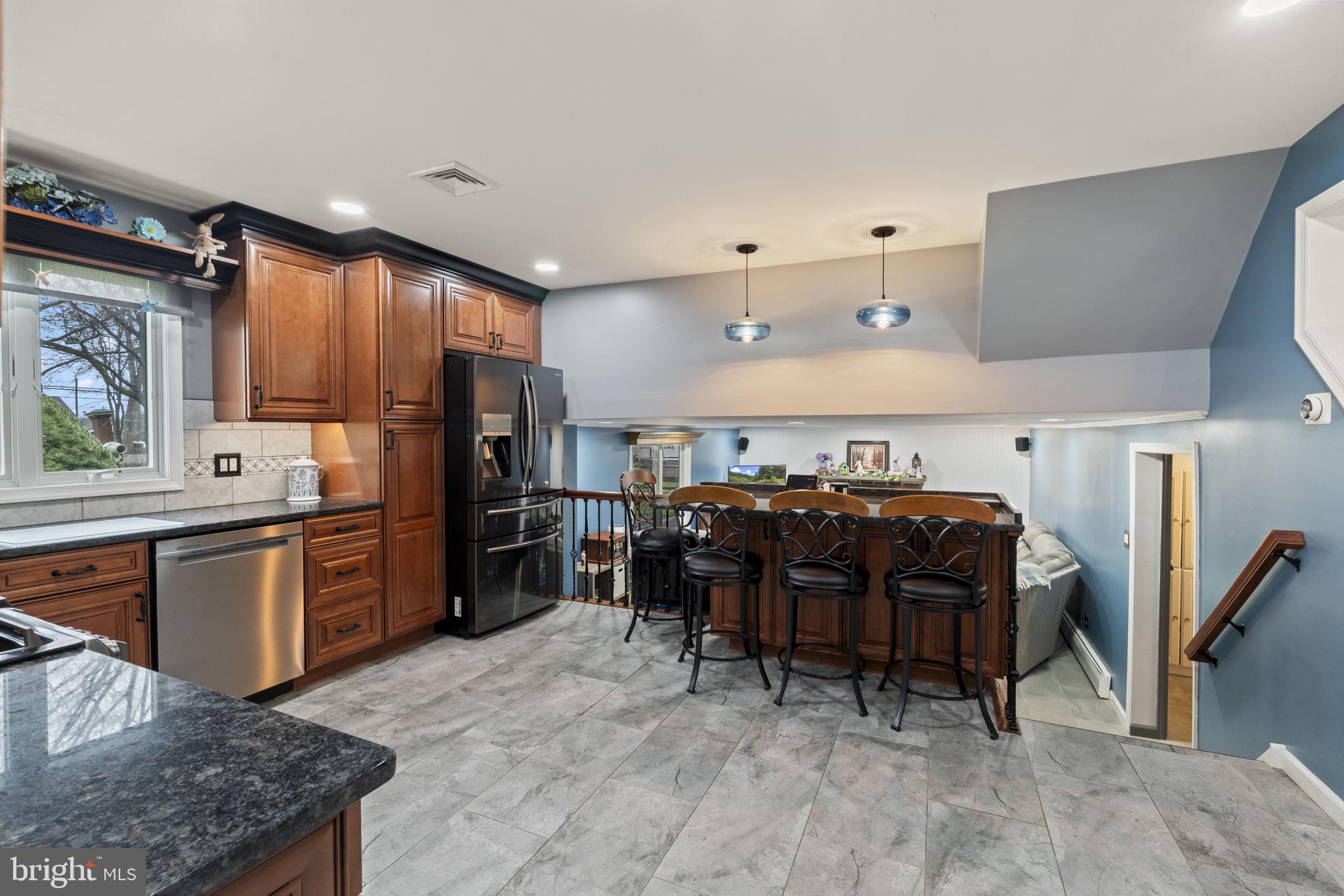 4901 Reedman Avenue Bensalem, PA 19020 - Photo 14 of 55 a kitchen with stainless steel appliances granite countertop a refrigerator oven stove a sink a dining table and chairs with wooden floor