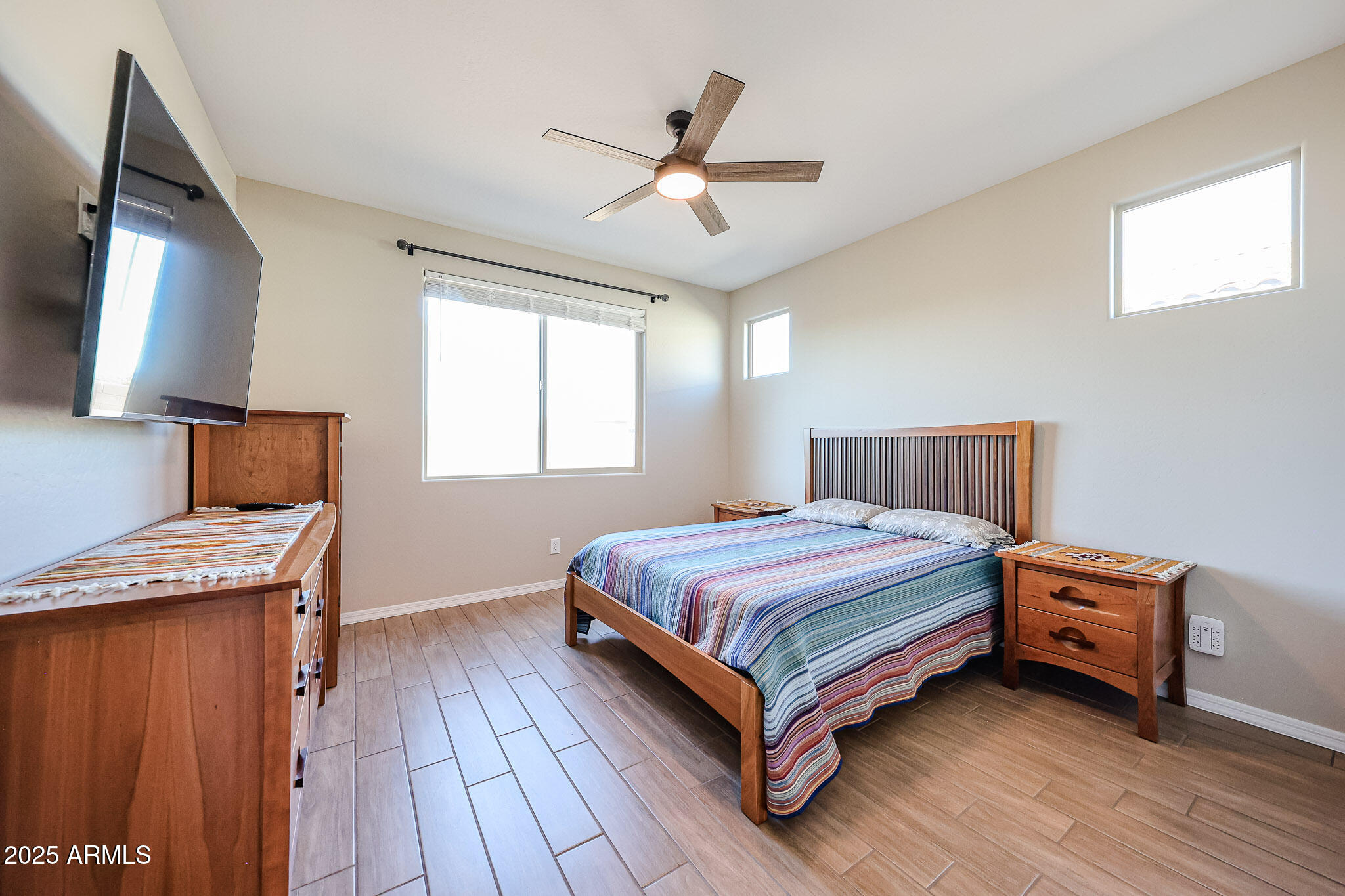 18062 West Amber Ridge Way Goodyear, AZ 85338 - Photo 18 of 67 a bedroom with a bed and a flat tv screen on dresser
