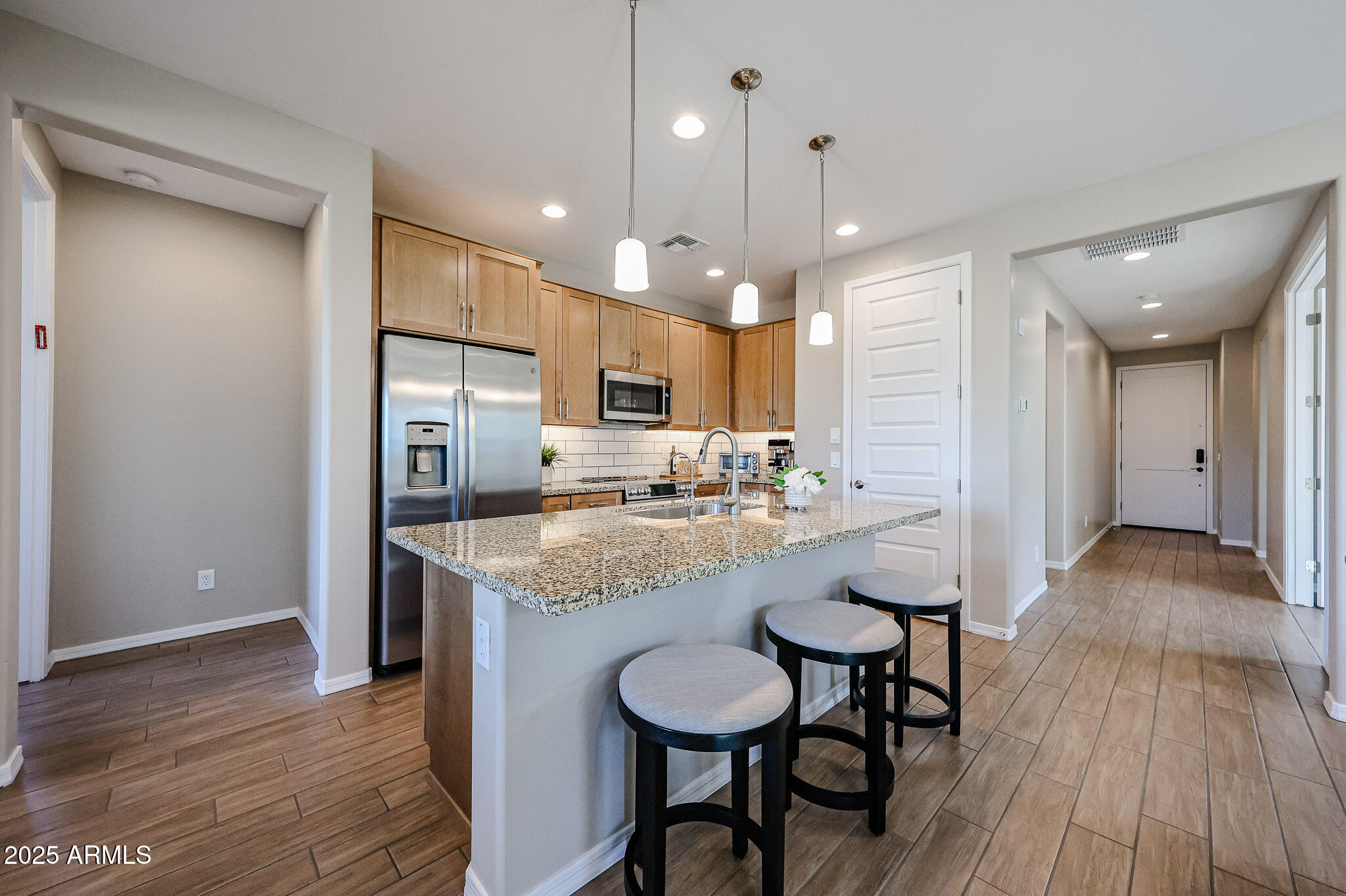 18062 West Amber Ridge Way Goodyear, AZ 85338 - Photo 7 of 67 a kitchen with stainless steel appliances granite countertop a kitchen island a stove a refrigerator a sink a dining table and chairs with wooden floor