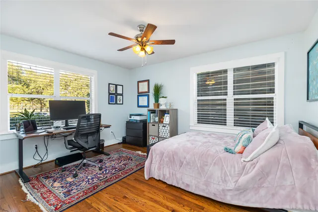 a bedroom with a bed a computer on desk and a dresser