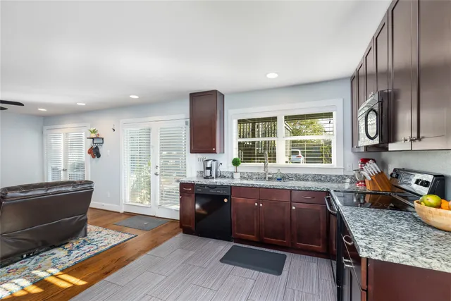 a large kitchen with granite countertop a stove a sink and dishwasher wooden cabinets with wooden floor