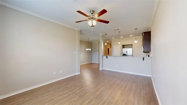 an empty room with wooden floor and a ceiling fan
