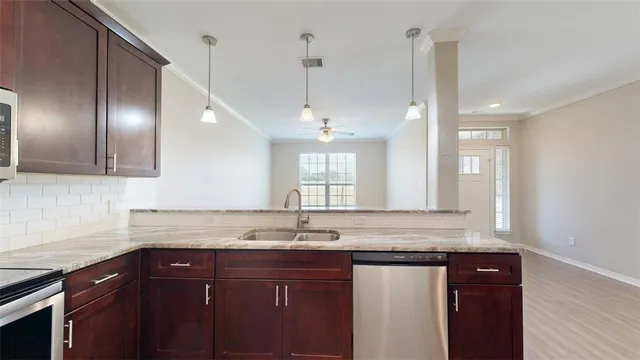 a sink with granite countertop cabinets and window