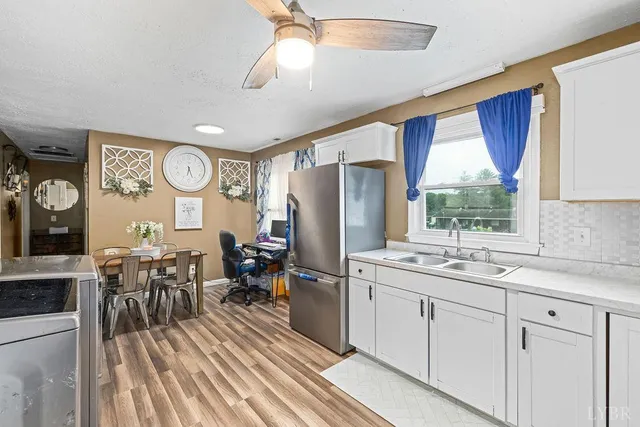 a kitchen with stainless steel appliances granite countertop a refrigerator a sink dishwasher a dining table and chairs with wooden floor