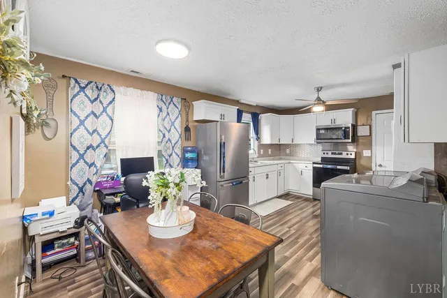 a kitchen with stainless steel appliances granite countertop a refrigerator a stove a sink a dining table and chairs with wooden floor