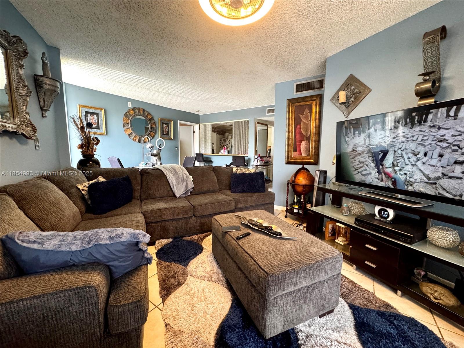 7165 Northwest 186th Street, Unit A211 Hialeah, FL 33015 - Photo 2 of 15 a living room with furniture and a flat screen tv