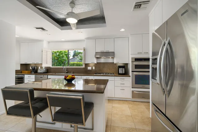 a kitchen with stainless steel appliances granite countertop a refrigerator a stove a sink dishwasher a dining table and chairs with wooden floor