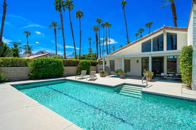 a view of a house with backyard sitting area and swimming pool