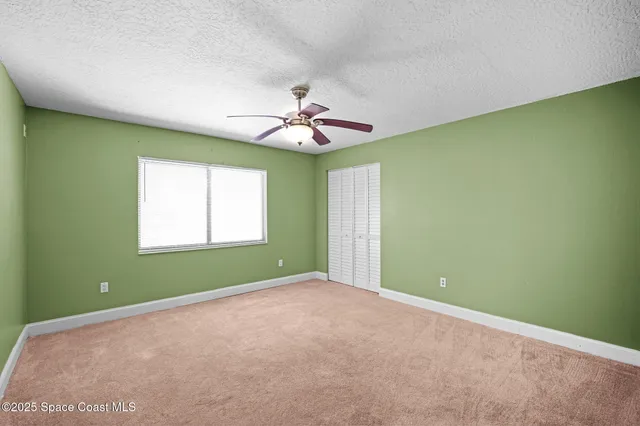 an empty room with a window and a fan