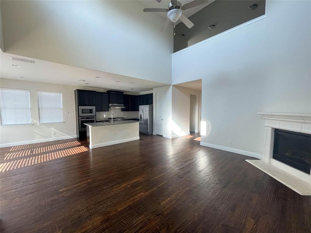 723 Callaway Drive Allen, TX 75013 - Photo 12 of 25 an empty room with wooden floor fireplace and windows