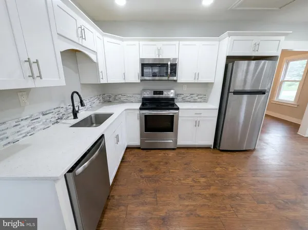 a kitchen with granite countertop a sink stove and refrigerator