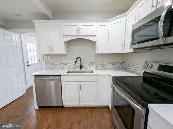 a kitchen with stainless steel appliances granite countertop a sink dishwasher a stove microwave and cabinets with wooden floor