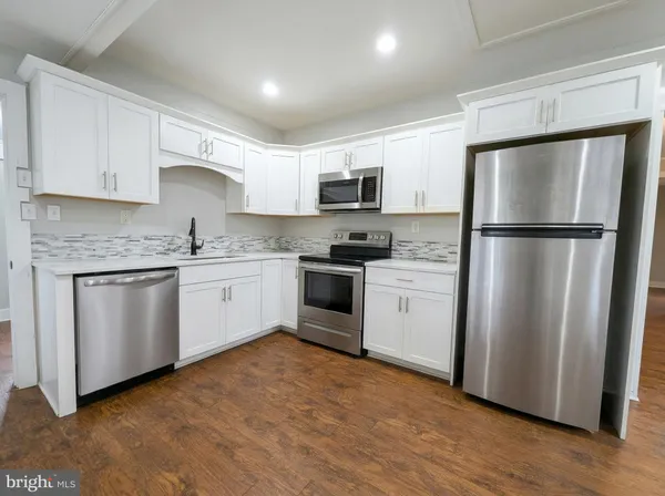 a kitchen with white cabinets white stainless steel appliances and wooden floors