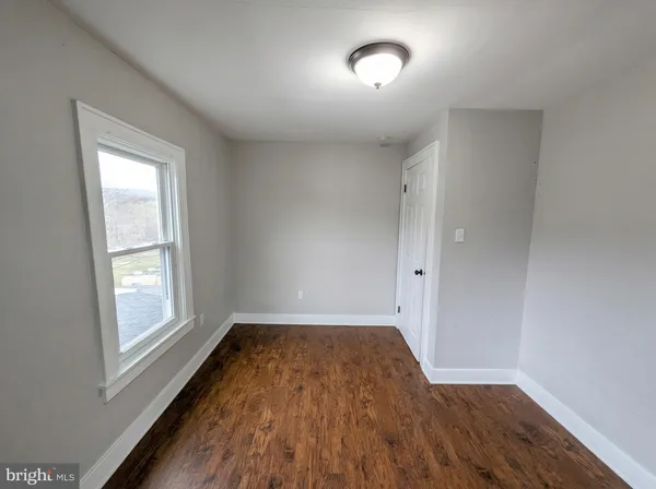 an empty room with a hardwood and windows