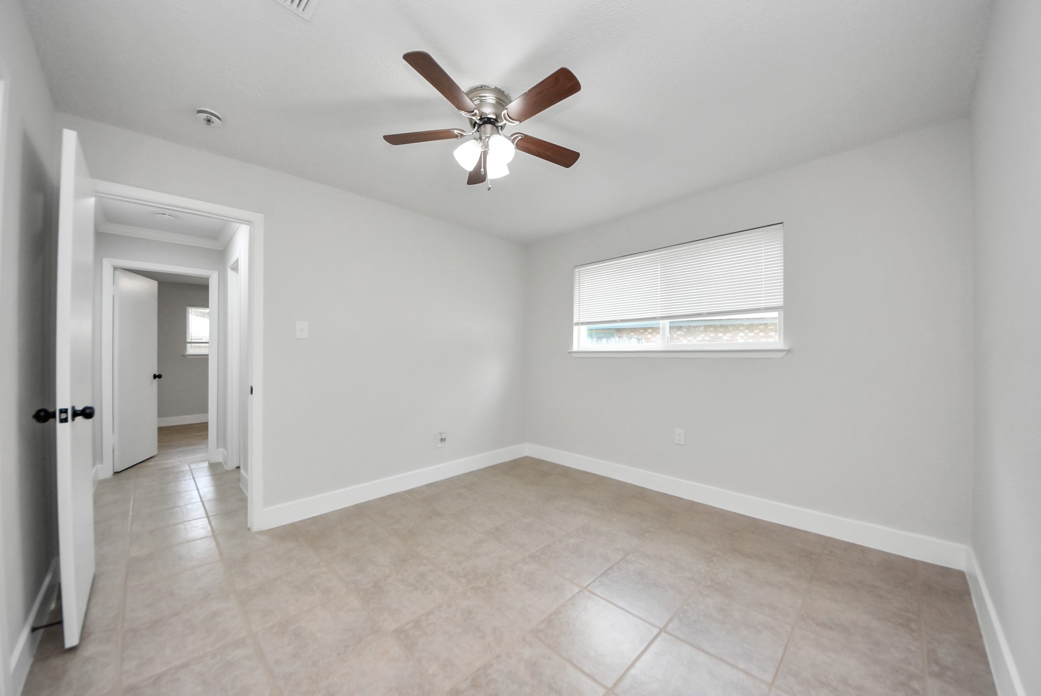 5314 Sweetwind Lane Spring, TX 77373 - Photo 34 of 47 Bedroom on the right featuring neutral tile flooring, a modern ceiling fan, and ample natural light from a wide window, perfect for creating a cozy living space.