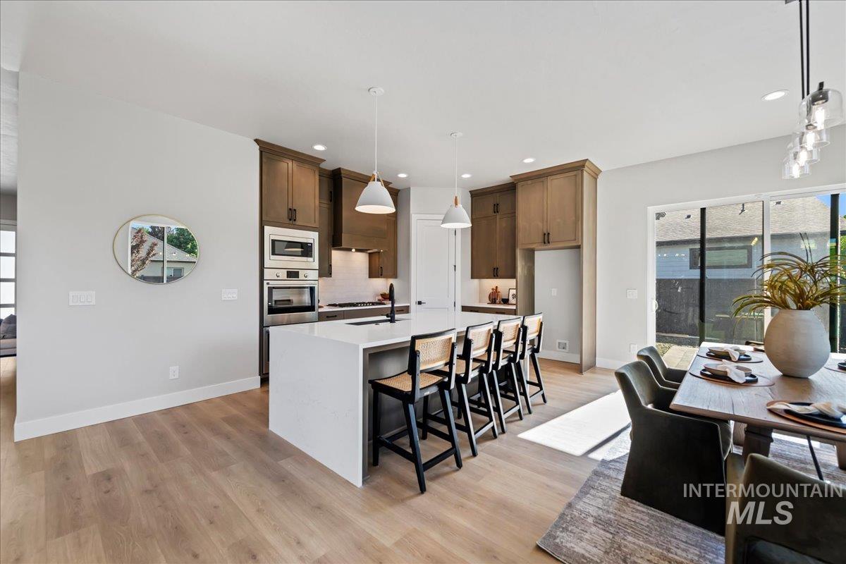 985 West Malbar Street Meridian, ID 83646 - Photo 13 of 39 Modern kitchen featuring a white center island with integrated seating, stainless steel appliances, wood-finish cabinetry, and light wood-finish flooring