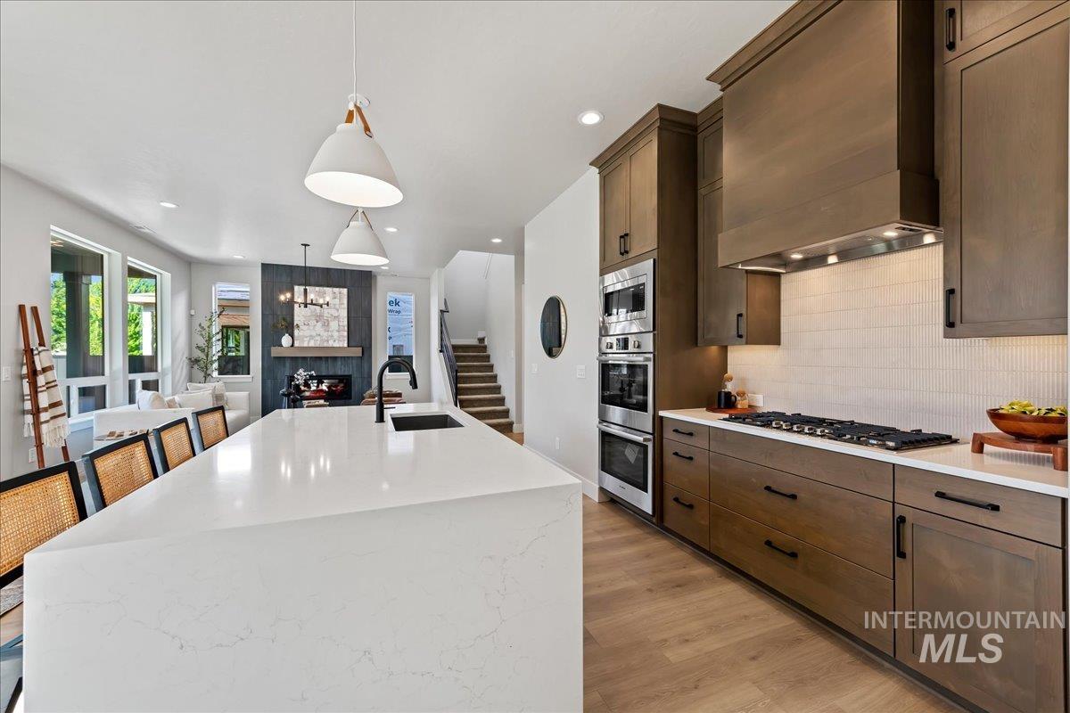 985 West Malbar Street Meridian, ID 83646 - Photo 15 of 39 Gourmet kitchen featuring a large white countertop island with integrated sink, wood-finish cabinetry, stainless steel appliances, and a gas cooktop