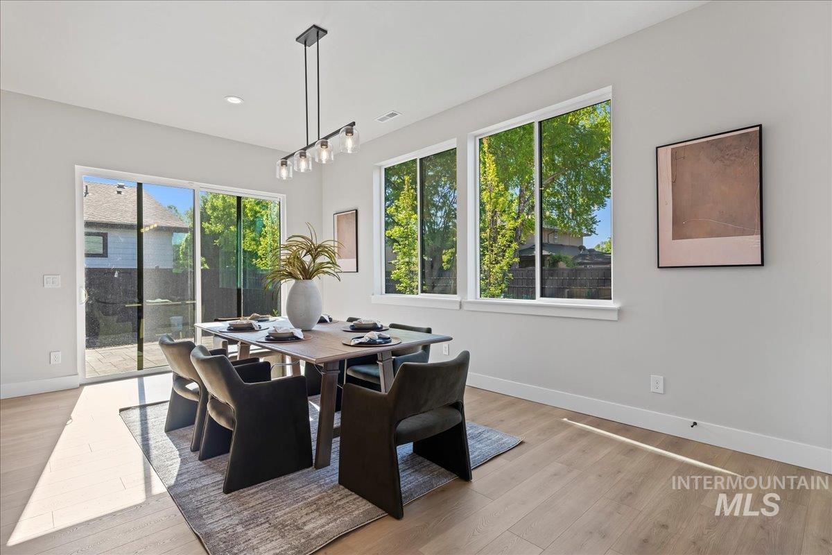 985 West Malbar Street Meridian, ID 83646 - Photo 16 of 39 Spacious dining area featuring wood-finish flooring, a modern linear chandelier, and ample natural light from multiple windows and a glass sliding door