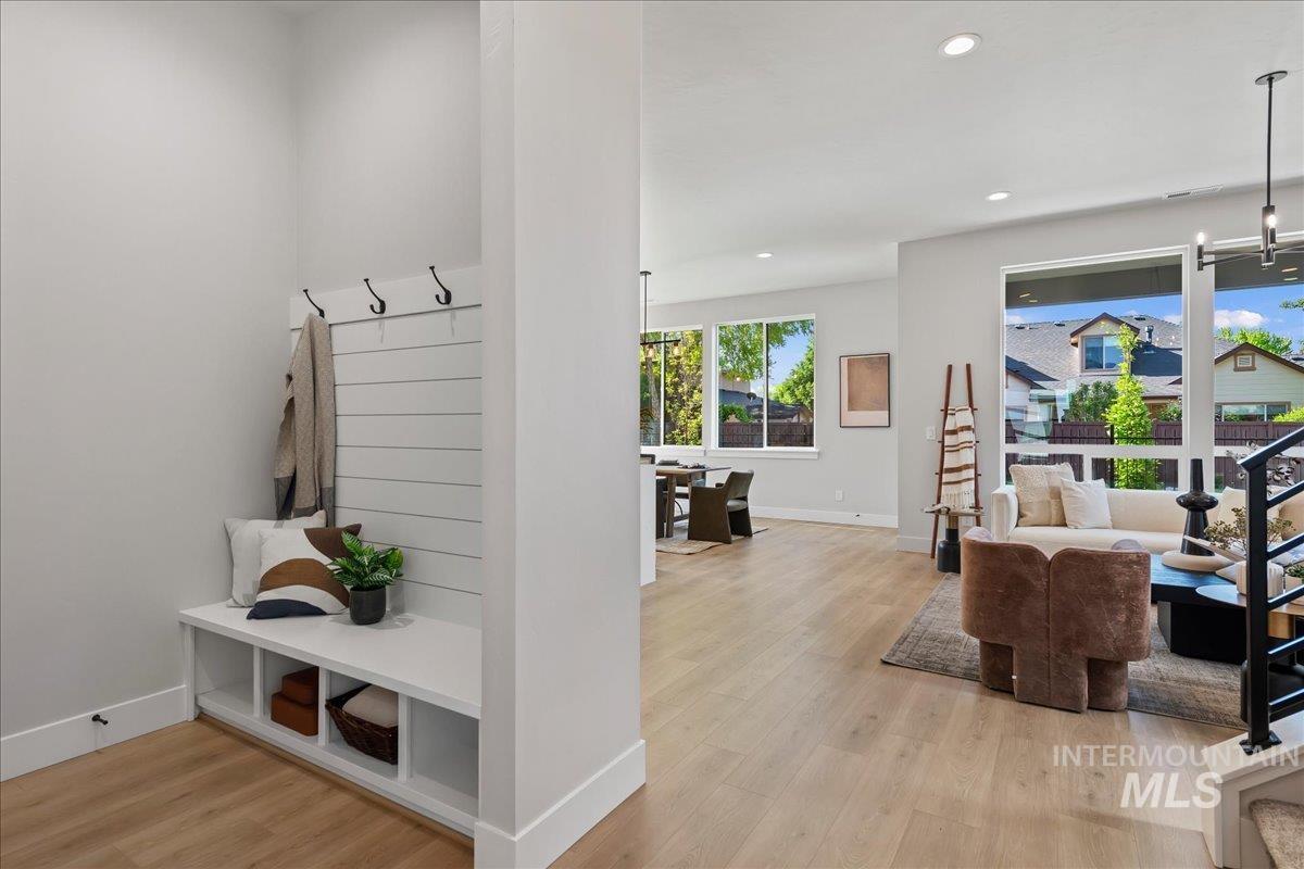 985 West Malbar Street Meridian, ID 83646 - Photo 17 of 39 Built-in entryway bench with cubby storage and coat hooks, wood-finish flooring, recessed lighting, expansive windows, and a black metal staircase railing