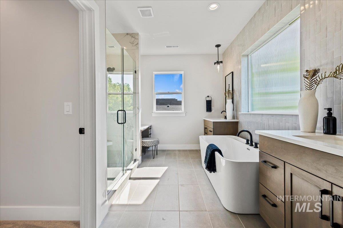 985 West Malbar Street Meridian, ID 83646 - Photo 21 of 39 Spacious bathroom featuring a freestanding soaking tub, a frameless glass shower enclosure, and dual vanity areas with ample counter space