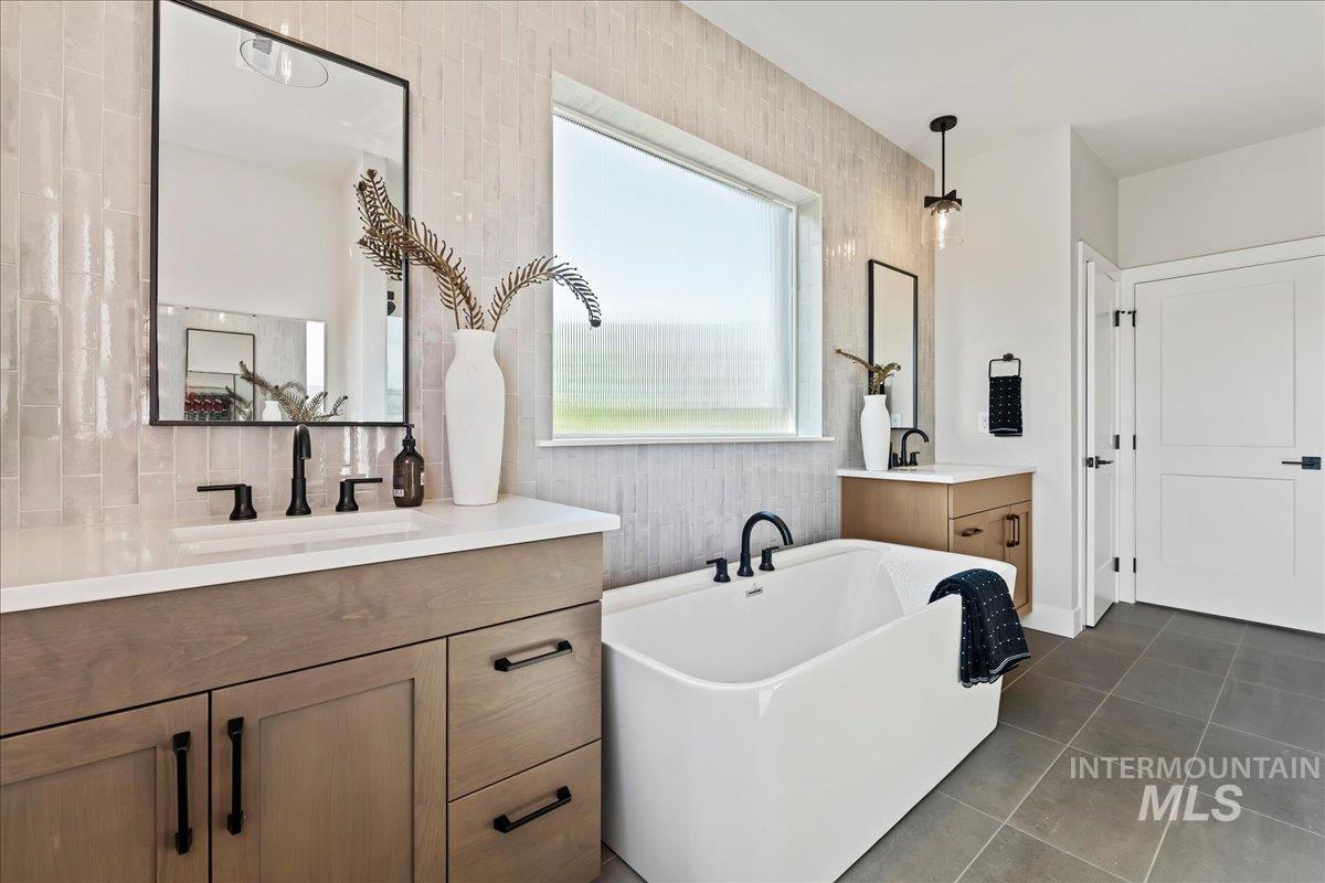985 West Malbar Street Meridian, ID 83646 - Photo 23 of 39 Freestanding soaking tub with matte black fixtures, complemented by dual wood-finish vanities with white countertops