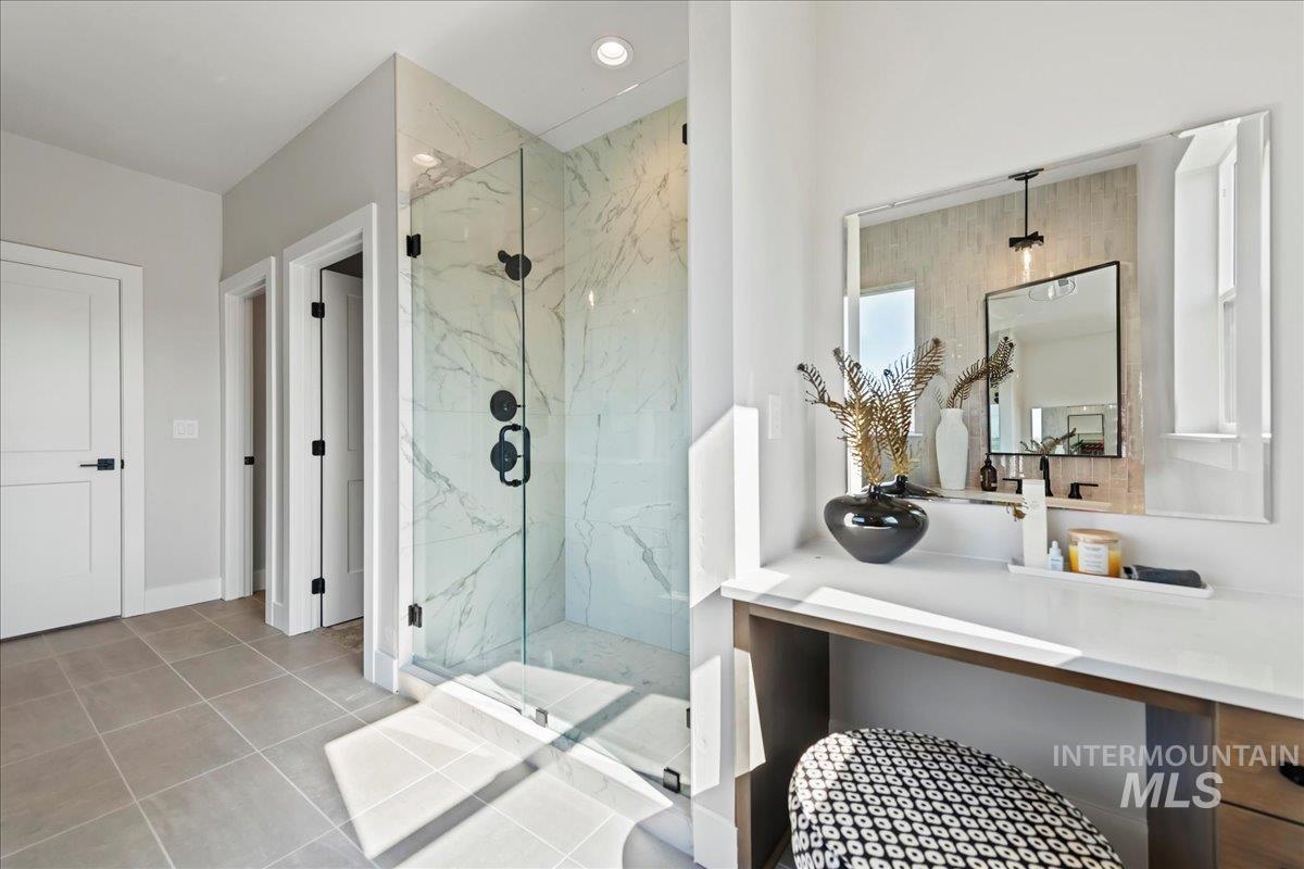 985 West Malbar Street Meridian, ID 83646 - Photo 24 of 39 Bathroom featuring a glass-enclosed shower with large format marble-look tile, matte black shower fixtures, a built-in vanity with a quartz countertop, and large format floor tiles