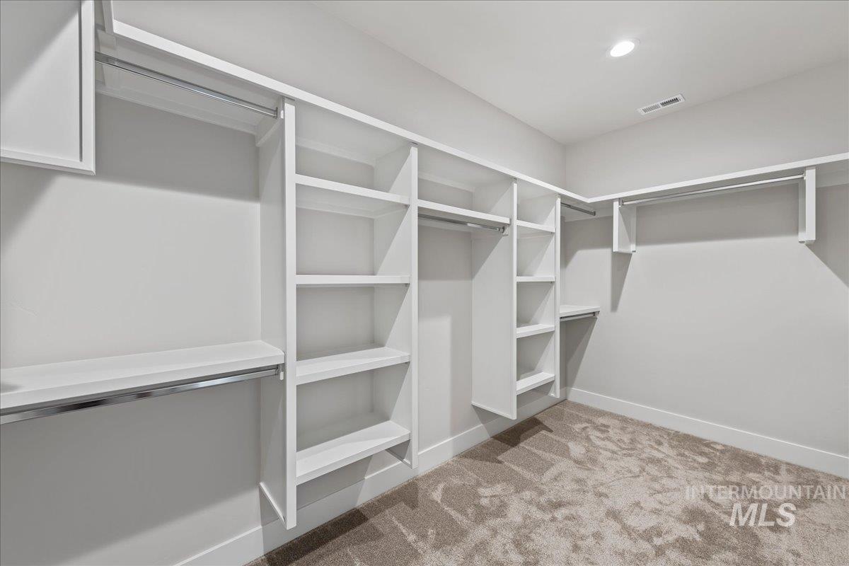 985 West Malbar Street Meridian, ID 83646 - Photo 25 of 39 Walk-in closet featuring built-in white shelving, hanging rods, recessed ceiling lighting, and light-toned carpeting