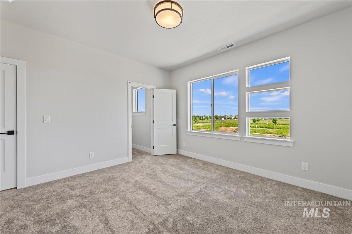 985 West Malbar Street Meridian, ID 83646 - Photo 29 of 39 Spacious interior room featuring light gray walls, plush gray carpet, a modern semi-flush ceiling light fixture, and multiple windows