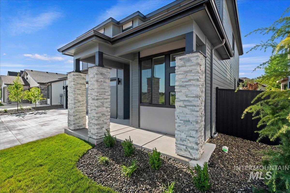 985 West Malbar Street Meridian, ID 83646 - Photo 3 of 39 Contemporary exterior featuring stacked stone columns, dark frame windows, and horizontal siding