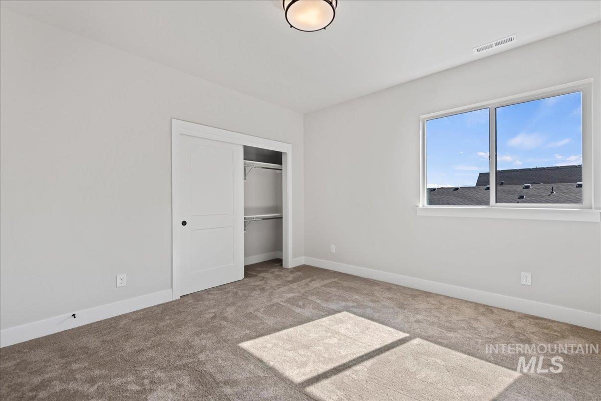 985 West Malbar Street Meridian, ID 83646 - Photo 31 of 39 Bright room featuring neutral carpet flooring, a large window, white trim, a built-in closet with shelving, and a flush-mount ceiling light fixture